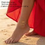 Woman wearing a Letter H Infinity Anklet with a double-layer chain and charm.