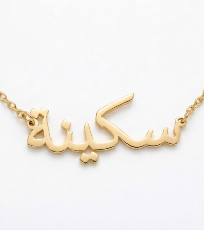 Copper necklace pendant spelling the name "Skina" in Arabic calligraphy