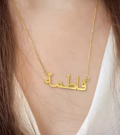 Copper necklace pendant spelling the name Fatima in Arabic calligraphy.