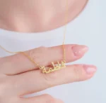 Copper necklace pendant spelling the name Fatima in Arabic calligraphy.