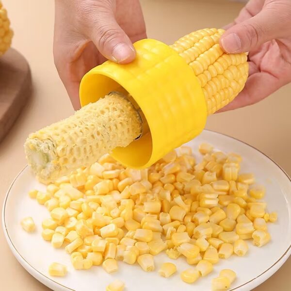 A person using the Stainless Steel Corn Stripper Peeler on a yellow corn cob.