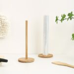 A standing light-colored wooden paper towel holder standing on a kitchen counter.