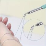 Retractable jewelry helper tool holding a gold bracelet for easy fastening.