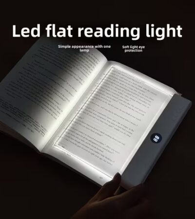 A transparent LED reading light panel placed over a paperback book page in a dark room.