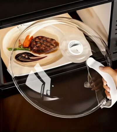 Two clear microwave food box covers over plates of broccoli and salad on a wooden table.