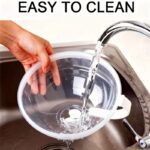 Two clear microwave food box covers over plates of broccoli and salad on a wooden table.