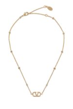 Close-up of Valentino Garavani Mini VLogo pendant with Swarovski crystals on a metal chain.