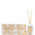 The Paris scented candle and fragrance diffuser are decorated with a powder pink and gold silk-screen print depicting the base of the Eiffel Tower's stylized structure.
