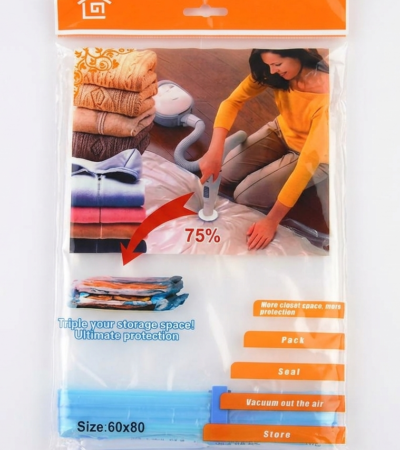 A transparent 60x80cm vacuum storage bag containing a folded blue quilt being compressed by a vacuum cleaner nozzle.