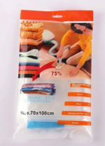 A vacuum cleaner nozzle compresses a folded blue quilt inside a transparent 70x100cm vacuum storage bag.