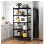 Five-tier black metal storage rack with wheels and cross-braced back standing in a modern kitchen.