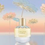 The elegant glass bottle of Elie Saab Girl of Now EDP featuring blue flower petal embellishments.