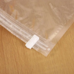 A transparent 60x80cm vacuum storage bag containing a folded blue quilt being compressed by a vacuum cleaner nozzle.