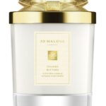 A Jo Malone London Orange Bitters Scented Candle in a limited-edition seasonal jar with a silver lid.