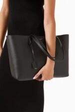 Saint Laurent East/West black leather tote bag with gold YSL charm and detachable pouch.