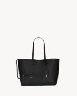 Saint Laurent East/West black leather tote bag with gold YSL charm and detachable pouch.