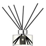 Sleek glass citrus diffuser bottle with 10 black reeds on a minimalist background.