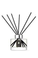 Sleek glass citrus diffuser bottle with 10 black reeds on a minimalist background.