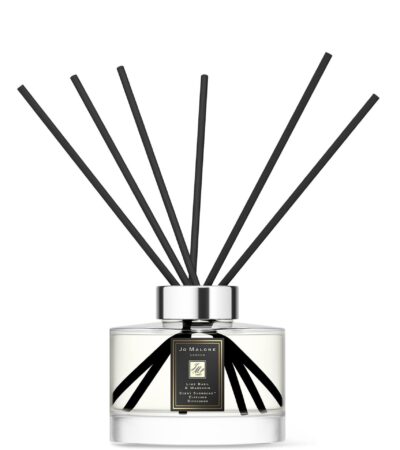Sleek glass citrus diffuser bottle with 10 black reeds on a minimalist background.