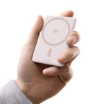 The pink Baseus PicoGo AM31 magnetic power bank attached to a phone using its built-in kickstand.