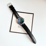 Gucci G-Timeless 36mm watch with Mother-of-Pearl dial and black leather strap.