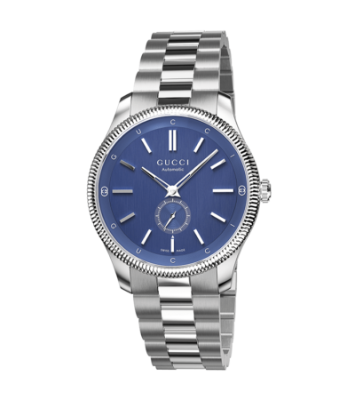 Gucci G-Timeless Slim 40mm automatic watch with blue dial, signature House motifs, and stainless steel bracelet.