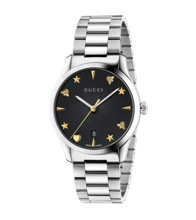 Gucci G-Timeless 38mm men's watch with black dial featuring bee and star motifs on a stainless steel bracelet.