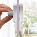 Double-sided magnetic window cleaner with safety cord on a glass pane