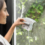Double-sided magnetic window cleaner with safety cord on a glass pane