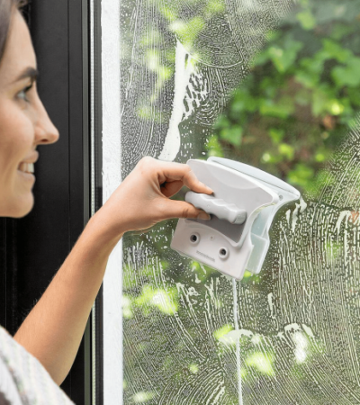 Double-sided magnetic window cleaner with safety cord on a glass pane